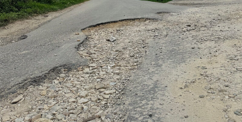 Damaged road with multiple potholes on the route connecting Royal Thimphu College.