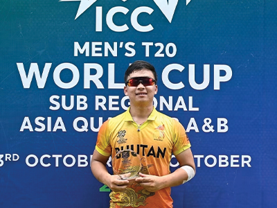 Bhutanese cricket player wearing the national team jersey and sunglasses while holding a trophy at the ICC Men’s T20 World Cup Sub-Regional Asia Qualifier