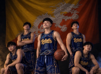 TCITY Goliaths basketball team posing in navy blue and gold jerseys with the Bhutan national flag in the background